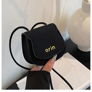 Close-up of mini black crossbody bag featuring yellow orin logo and slim cord strap