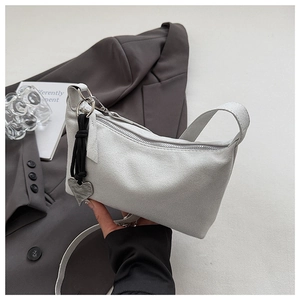 Close-up of light gray suede shoulder bag with silver zipper and heart pendant detail