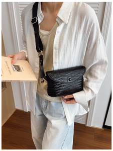 Détail du sac bandoulière tressé noir avec large sangle en tissu sur un mannequin