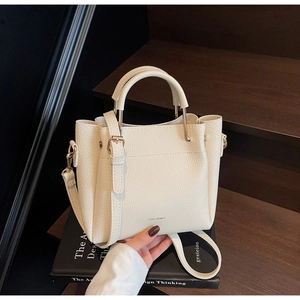 Detail of creamy white pebble leather bucket bag with gold hardware on art books