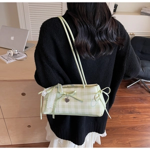 Close-up of light green plaid shoulder bag with white lace trim and bow detail