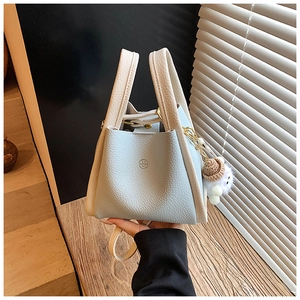 Detail of lychee pattern leather bucket bag with cute plush hat charm accessory