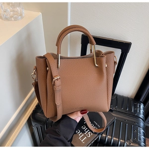 Detailed close-up of brown lychee leather bucket bag with gold hardware and logo