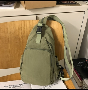 Detail of a grass green nylon sling bag showing a side pocket and adjustable buckle