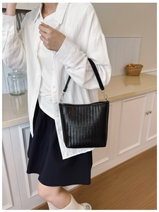 Détail de la texture tissée noire du sac seau avec boucle argentée et plaque de marque