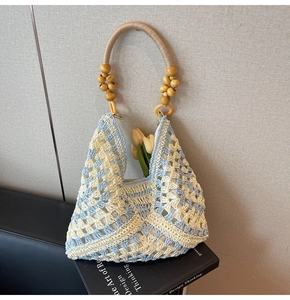 Macro detail of hand-woven geometric blue and beige tote bag with wooden bead handle
