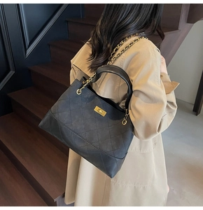 Close-up of black quilted shoulder bag with gold twist lock and leather chain strap