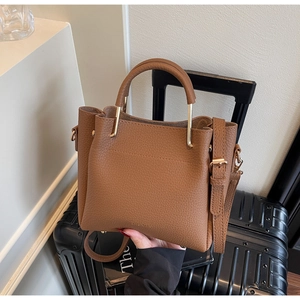 Detail view of brown lychee grain leather bucket bag with gold hardware and ZNRRMA logo
