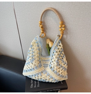 Detailed close-up of woven crochet tote bag with wooden flower beads and blue motifs
