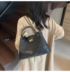 Classic black quilted tote bag with gold chain strap shown as crossbody on a model