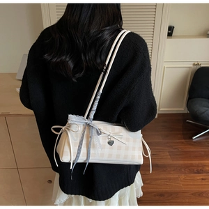 Rear view of a cream checkered shoulder bag with decorative bow and heart charm details