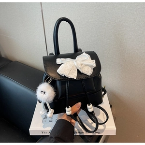 Detail of black mini backpack with lace bow, drawstring beads, and plush toy charm