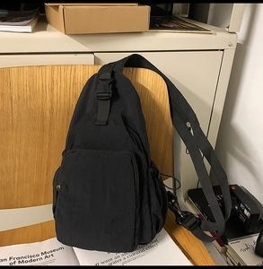 Close-up of black nylon crossbody chest bag with multiple zipper pockets and buckles