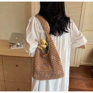Détail du sac à bandoulière tressé marron ajouré porté par un mannequin sur l'épaule