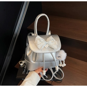 Detail of silver faux leather backpack with white lace bow and plush doll accessory