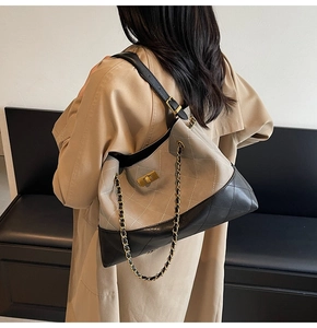 Detailed close-up of quilted beige and black leather crossbody bag with chain strap