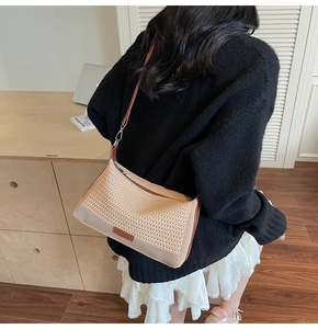 Dettaglio della borsa a tracolla beige intrecciata con finiture in pelle marrone e zip