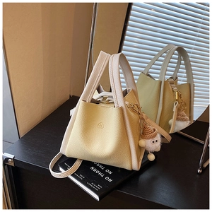 Close-up of litchi texture bucket bag with dual-tone design and plush pendant