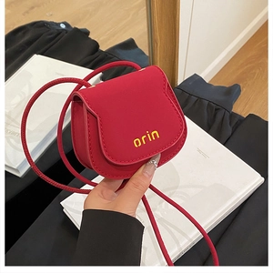 Detailed close-up of a mini red leather crossbody bag with yellow orin logo branding