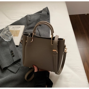 Detailed shot of beige lychee leather crossbody bucket bag with golden hardware accents