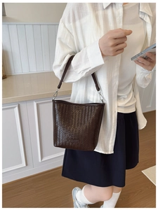Détail de la texture en cuir tressé marron foncé et logo embossé sur le sac seau