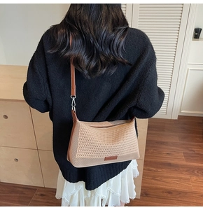Dettaglio borsa in maglia beige con finiture in pelle marrone e gancio in metallo
