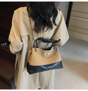 Detail of quilted khaki and black chain bag worn with a coat for casual styling
