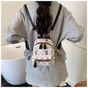 Vue arrière d'un mannequin portant le mini sac à dos crème aux motifs de dessins animés