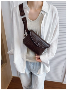 Détail du sac de poitrine en cuir tressé marron foncé avec large bandoulière