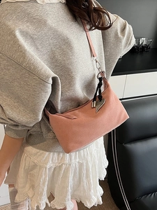 Pink suede crescent hobo bag with heart pendant shown on model in modern room