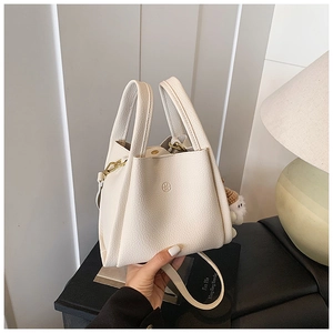 Close-up of cream lychee leather bucket bag featuring a circular embossed U.M logo