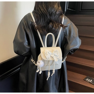 Detailed back view of a white mini backpack featuring a lace bow and cute pompom charm