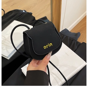 Detailed close-up of a mini black crossbody bag with a distinctive yellow orin logo print