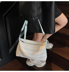 Dettaglio borsa a tracolla in rete bianca con cinturino in pelle azzurra sulla modella