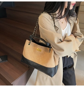 Detail of quilted tote bag with golden twist-lock closure and leather chain strap