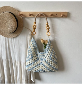 Detail of blue and white woven crochet tote with wooden bead handle on a rustic hook