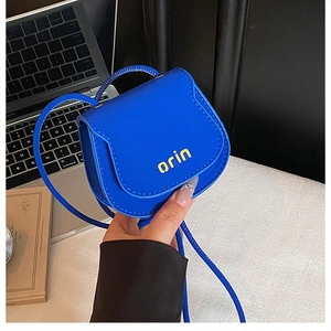 Macro shot of electric blue micro saddle bag with yellow logo for fashion styling