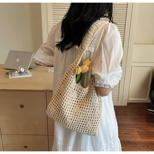 Gros plan d'un sac cabas en crochet crème porté par un mannequin dans un cadre intérieur