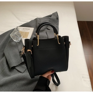 Detail of black lychee grain leather bucket bag with gold metal handle and logo