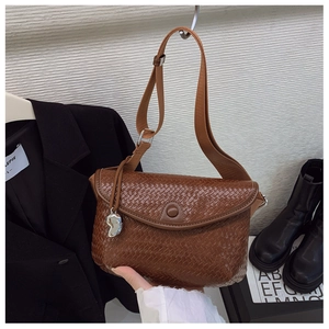 Détail du sac bandoulière marron tressé avec breloque en métal et sangle réglable