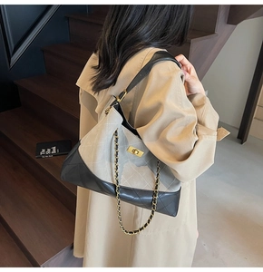 Close-up of grey suede and black quilted leather tote bag with gold metal twist lock