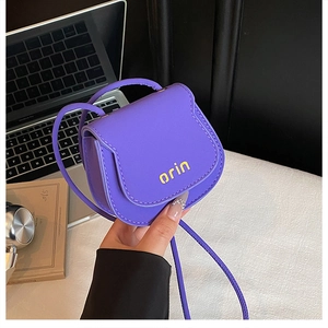 Close-up detail of a purple mini saddle bag with yellow orin logo and slim shoulder strap