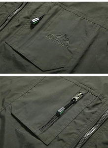 Detail of outdoor fishing vest showing military green fabric and mountain embroidery