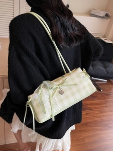 Green plaid shoulder bag with white lace trim and bow accent in a stylish setup