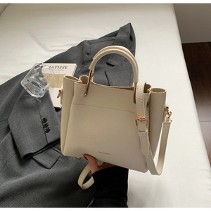 Macro shot of cream bucket bag showing lychee grain leather texture and gold hardware