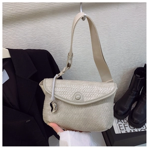 Détail du sac à bandoulière tressé beige avec sangle large et pendentif argenté