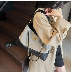 Detail of grey suede and black leather tote bag with quilted stitching and chain strap