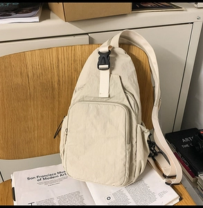Detail of off-white nylon crossbody bag showing the front pocket with plastic buckle strap