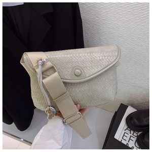 Détail du sac bandoulière tissé beige clair avec breloque cœur et large sangle