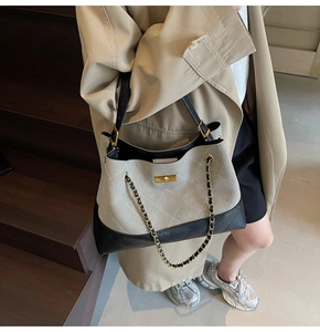 Detail of the quilted texture and golden twist lock on a gray suede shoulder bag